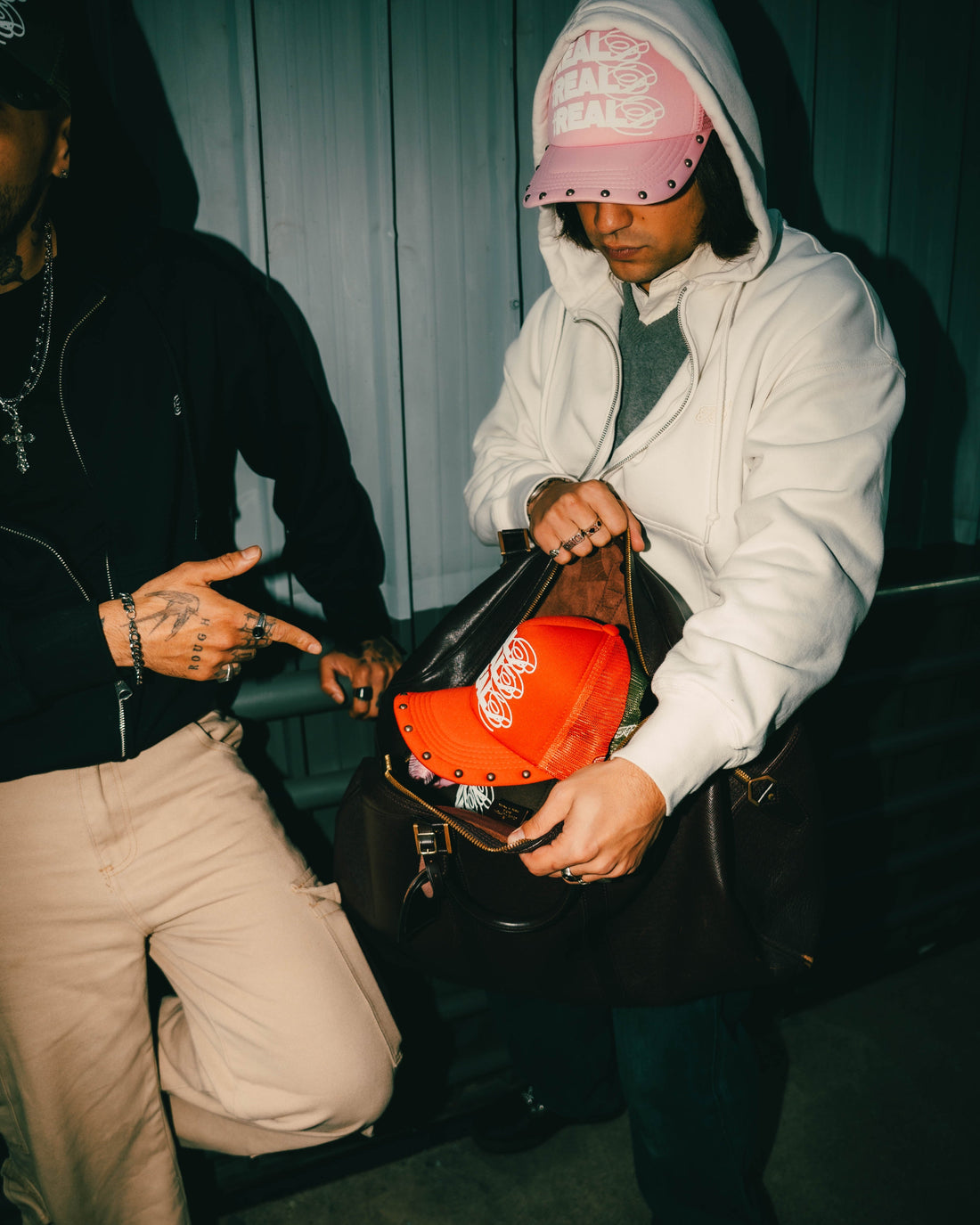 Persona con bolso abierto y la otra apuntando al gorro rojo de Reales Bendecidos